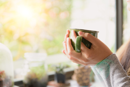 Woman hands holding hot cup of coffee or tea in morning.の写真素材