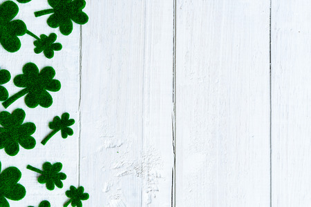 Happy St Patricks Day message and a lot of green paper clover leaf on white wooden backgroundの写真素材