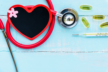 World health day, Healthcare and medical concept. Stethoscope, red and black heart, thermometer and yellow Pill on Pastel white and blue wooden table background texture.の写真素材