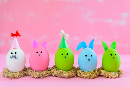 Row Easter eggs with colorful paper flowers on bright pink and white wooden background.の写真素材