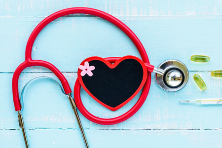 World health day, Healthcare and medical concept. Stethoscope, red and black heart, thermometer and yellow Pill on Pastel white and blue wooden table background texture.の写真素材