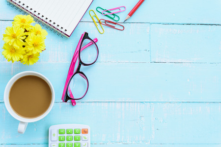 Top view office table with workspace and office accessories including calculator, mouse, keyboard, glasses, clips, flower, pen, pencil , note book and laptop on bright green wooden background.の写真素材