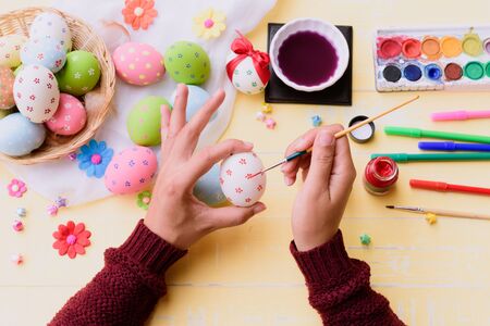 Happy easter! A woman hand painting Easter eggs. Happy family preparing for Easter.の写真素材