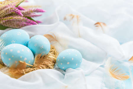 Happy easter! Colorful of Easter eggs in nest with flower,  paper star and Feather on white cheesecloth background.の写真素材