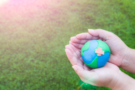 World Earth Day April 22 concept. Woman hand holding handmade globe on green grass field background.の写真素材
