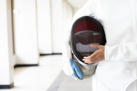 Close-up of a fencer in white fencing suit and hand holding her mask.の写真素材