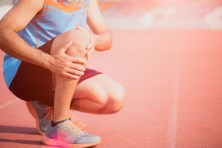 knee Injuries. young sport man with strong athletic legs holding knee with his hands in pain after...
