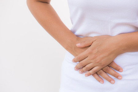 Young beautiful woman having painful stomachache on white background.Chronic gastritis. Abdomen bloating concept.の写真素材