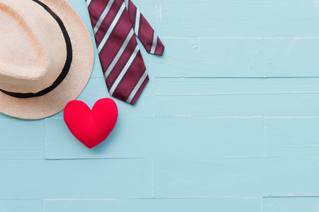 Happy fathers day concept. Red tie, man hat and handmade red heart on bright blue pastel wooden table background.の写真素材