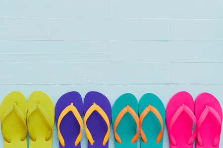 Beach accessories including colorful flip flop on bright blue pastel wooden background for summer holiday and vacation concept.の写真素材