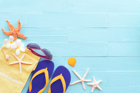 Beach accessories including sunglasses, starfish, green towel, flower, colorful flip flop and sea...