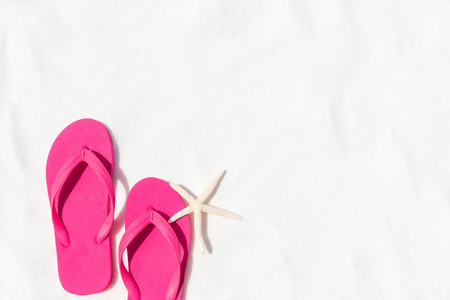 Pink flip flop put or step on on White sandy beach background with starfish for summer holiday and vacation concept.の写真素材