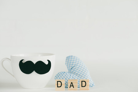Happy fathers day concept. Handmane red heart with mustache and bow tie on coffee cup with wooden...