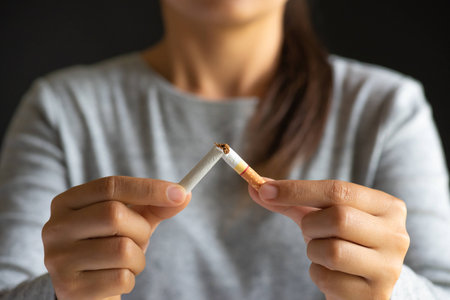 World No Tobacco Day, May 31. STOP Smoking. Close up woman hand breaking, crushing or destroying cigarettes on black background.の写真素材