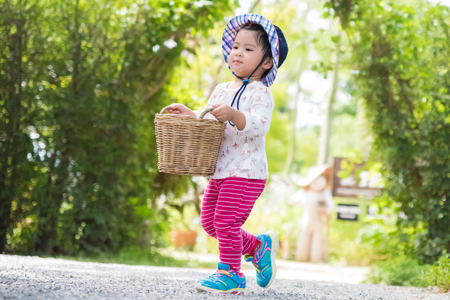 Happy little girl running with basket the garden farm. Summer activities for kids.の写真素材
