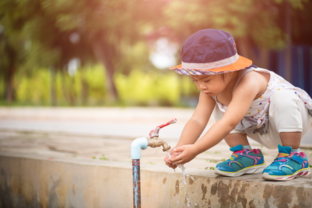 Water pouring in little girl's hands. World Water Day concept.の写真素材