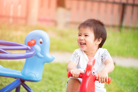 Happy little girl having fun on a playground enjoying a swing ride on a hot summer day in a sunny city park.の写真素材