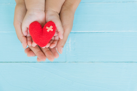 Top view of adult and child holding red heart in hands, Happy family relationships, Valentine's day, Mother's Day, Love and health care concept.の写真素材