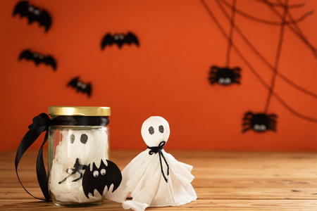 Halloween crafts, ghost and spide on wooden table and orange background with copy space for text. halloween concept.の写真素材