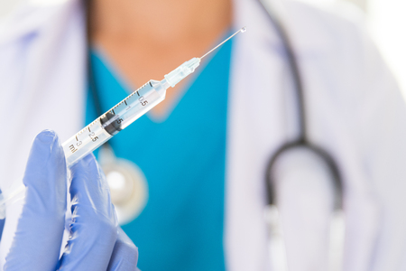 Female doctor with a stethoscope on shoulder holding syringe and vaccine. Healthcare And Medical concept.の写真素材