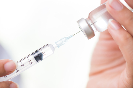 Female doctor with a stethoscope on shoulder holding syringe and vaccine. Healthcare And Medical concept.の写真素材