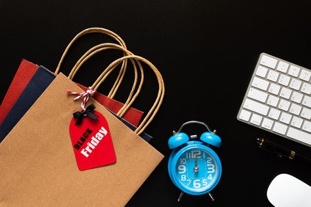 Black Friday Sale text on a red tag with keyboard computer, mouse and Alarm Clocks on black background. Shopping concept.の写真素材