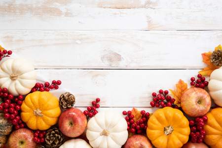 Top view of  Autumn maple leaves with Pumpkin and red berries on white wooden background....
