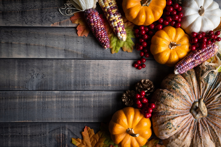 Top view of  Autumn maple leaves with Pumpkin, apple, corn and red berries on old wooden background. Thanksgiving day concept.の写真素材