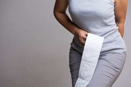 Woman hand holding her bottom and tissue or toilet paper roll. Disorder, Diarrhea, Constipation. Healthcare concept.の写真素材