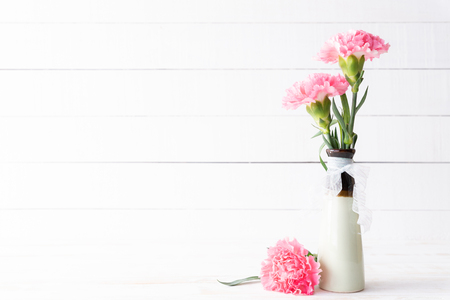 Valentines day and love concept. Pink carnation flower in vase on white wooden background.の写真素材