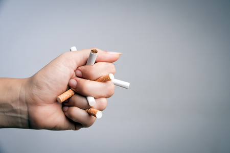 World No Tobacco Day, May 31. STOP Smoking. Close up Man hand crushing and destroying cigarettes on gray background.の写真素材