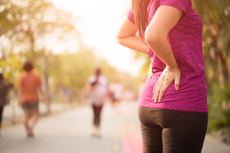 Young asian woman feel pain on her back and hip while exercising, health care concept.の写真素材