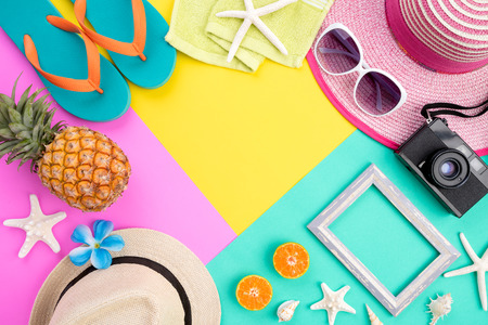 Beach accessories retro film camera, pineapple, sunglasses, flip flop starfish beach hat and sea shell on pink and yellow background for summer holiday and vacation concept.の写真素材