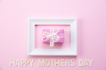 Happy mother's day concept. Top view of picture frame and gift box with happy mothers day text on pink pastel background. Flat lay.の写真素材