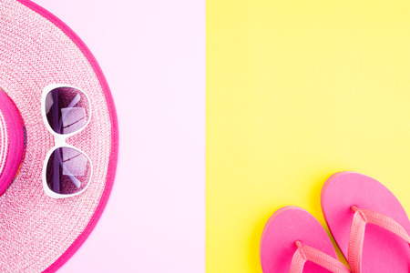 Beach accessories sunglasses, flip flop starfish beach hat and sea shell on pink and yellow background for summer holiday and vacation concept.の写真素材
