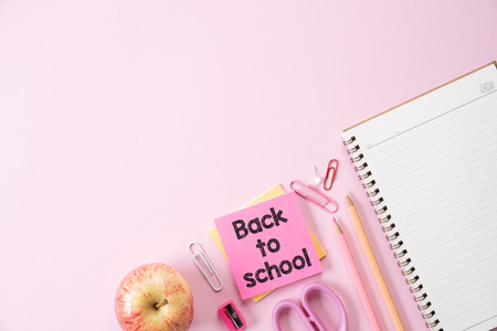 Education or back to school Concept. Top view of Colorful school supplies with books, color pencils, calculator, pen cutter clips and apple on pink pastel background. Flat lay.の写真素材