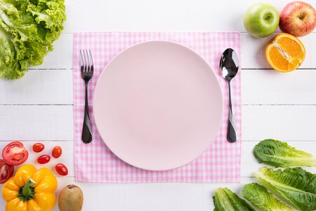 Healthy lifestyle and food concept. Top view of fresh vegetables, fruit, herbs and spices with a empty pink pastel plate on white wooden background.の写真素材