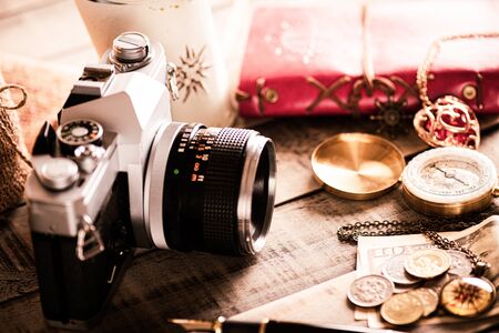 vintage items, pen red book, coins money, compass and retro photo film camera on wood background.