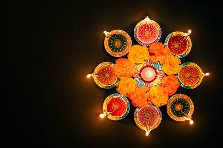 Happy Diwali - Clay Diya lamps lit during Dipavali, Hindu festival of lights celebration. Colorful traditional oil lamp diya on white backgroundの写真素材