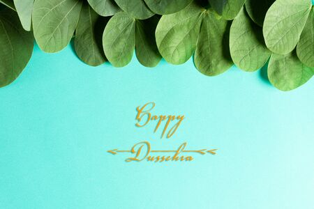 Happy Dussehra. Yellow flowers, green leaf and rice on blue pastel background. Dussehra Indian...