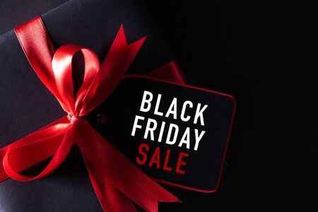 Top view of black christmas boxes with red paper tag on black background with copy space for text. black Friday composition.の写真素材