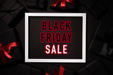 Top view of Black Friday Sale text on white picture frame with black gift box red ribbon and Christmas ball. Shopping concept and black Friday composition.の写真素材