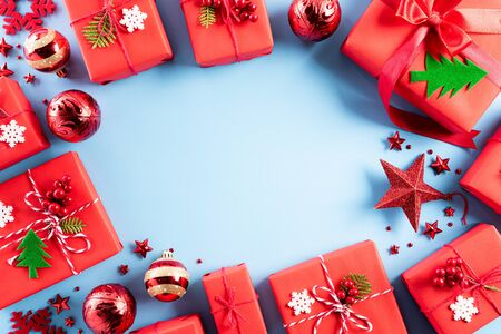 Christmas background concept. Top view of Christmas red gift box with candy cane, snowflakes, red berries and bell on blue pastel background.の写真素材