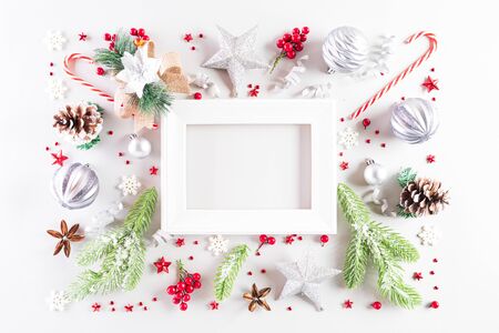 Christmas holidays composition Top view of white picture frame with gift box, Christmas tree decoration and red berries on white background with copy space for text.の写真素材