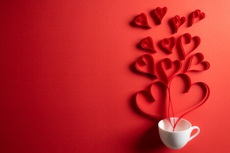 Red paper hearts splash out from white coffee cup on red paper background. Love and Valentine's day concept.の写真素材
