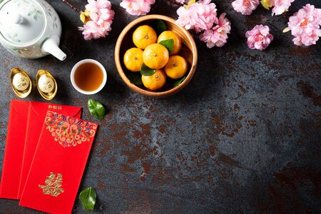 Chinese new year festival decorations pow or red packet, orange and gold ingots or golden lump on a black stone texture background. Chinese characters FU means fortune good luck, wealth, money flow.の写真素材