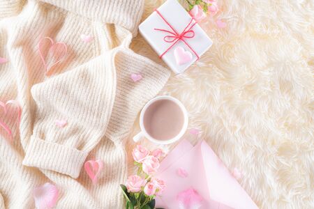 Pink paper hearts with gift box and roses, coffee cup on , beige sweater on cream colour knitted blanket and fluffy background. Love and Valentine's day during Winter concept.の写真素材