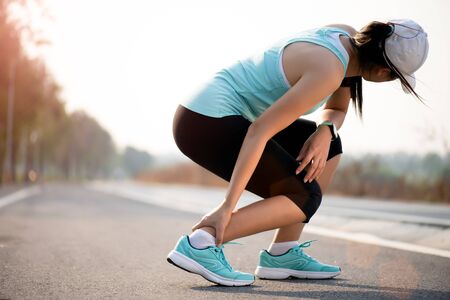 Ankle sprained. Young woman suffering from an ankle injury while exercising and running. Healthcare and sport concept.の写真素材