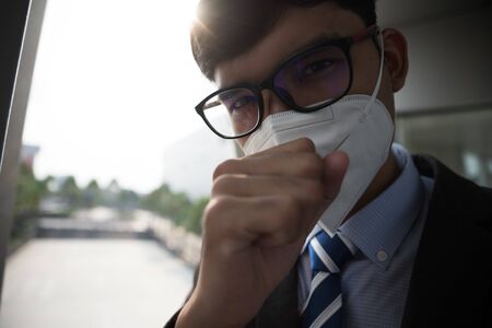 Close up of a businessman in a suit wearing Protective face mask and cough, get ready for Coronavirus and pm 2.5 fighting against in city background.の写真素材