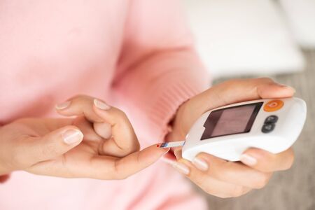Close up of woman hands checking blood sugar level by Glucose meter for diabetes tester using as Medicine, glycemia, healthcare and medical concept.の写真素材